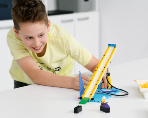 Chłopiec buduje pochyły model z lego education i przygląda mu się uważnie.