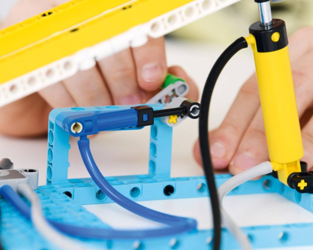 model maszyny z klocków lego education, uczeń wprawia w ruch mechanizm