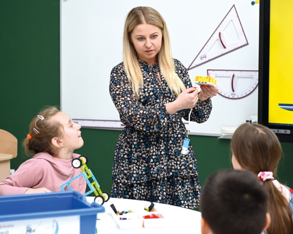 nauczycielka na lekcji tłumaczy uczniom jak podłączyć silniki do sterownika lego education