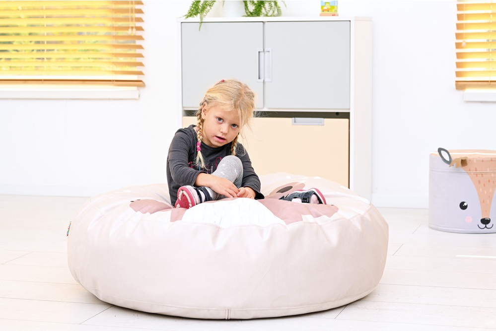 smutna dziewczynka siedząca na duzej pufie